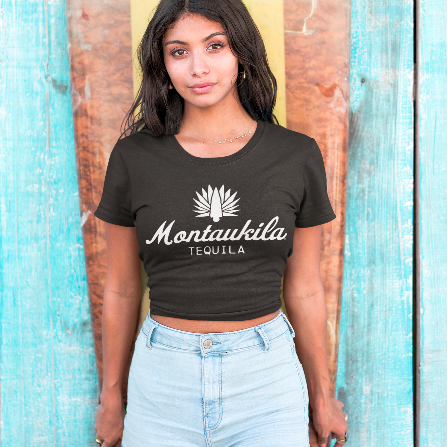 Woman wearing a black t-shirt with 'Montaukila Tequila' logo against a wooden background